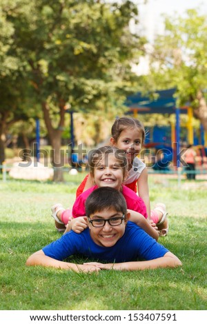 Happy children of three playing piggy back, looking at the camera.