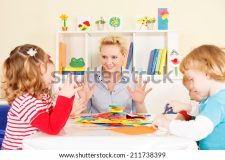 Preschool: Young smiling teacher discussing with group of children. Learning and having fun. Selective focus to teacher talking.