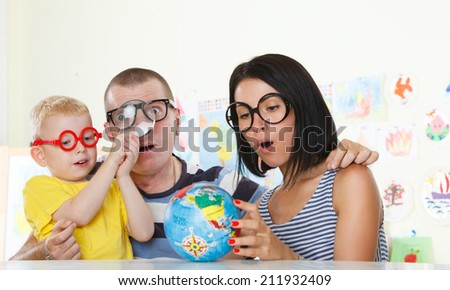 Family with glasses studying a globe with magnifier