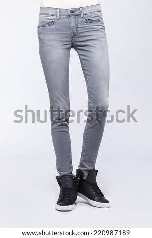 Front view of a standing woman(female) model wearing grey denim(trousers) with boots and white top isolated on a white background