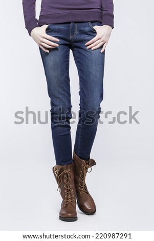 Front view of a standing woman(female) model wearing denim(trousers) with boots isolated on a white background