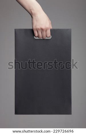 A female(woman) hand hold a black shopping bag(paper bag) at the studio.