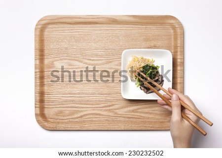 A female hand hold vegetable food(spinach, bean sprouts, mushroom) with chopsticks on the wood tray isolated white, top view at the studio.