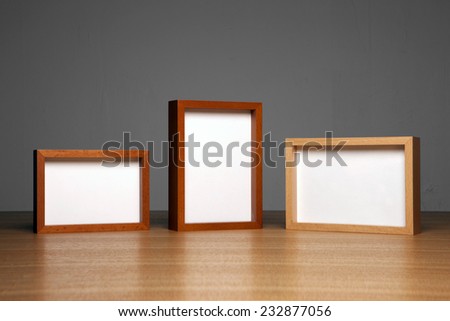 three empty(blank) wood photo frames(teak, cherry, oak) on the wood table(desk) at the studio.
