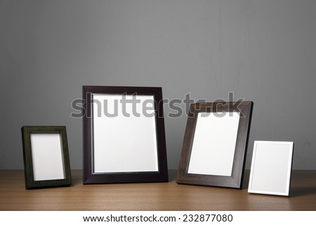Four empty(blank) wood photo frames(walnut, steel) on the wood table(desk) at the studio.