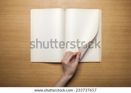 A female hands hold(grip) a vintage(old) book(note, diary) spread and through the pages of a book on the wooden desk, top view at the studio.