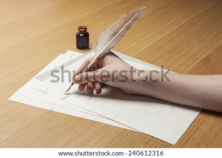 A female(woman) hand hold(write) a feather quill pen with ink on the letter paper and wood desk(table) at the studio.