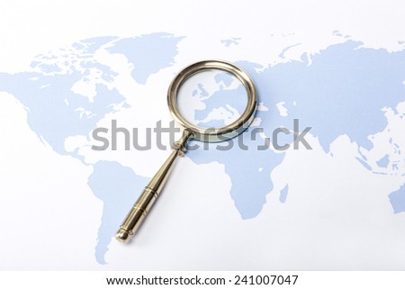 A gold vintage(classic, old) magnifier(reading glass) focus in europe on the blue world map.