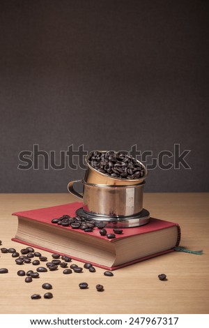 Coffee beans and old(vintage, classic) book and coffee dripper on the wood table(desk).