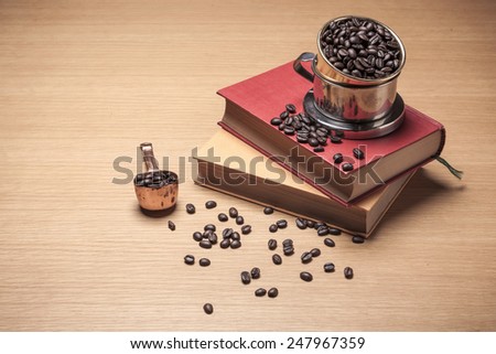 A coffee brass spoon with coffee beans and old(vintage, classic) book and coffee dripper on the wood table(desk).