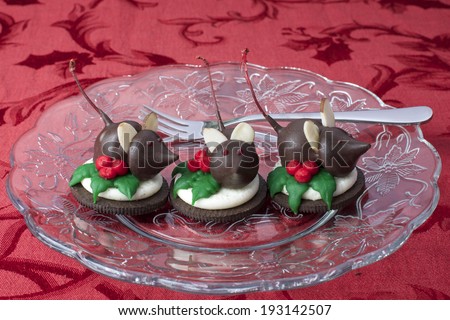 Home made Holiday Chocolate Candy Mice on a cookie with frosting holly leaves and berries. Body is a Maraschino Cherry with stem for the tail.