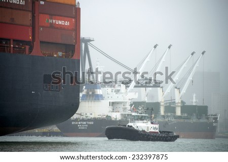 OAKLAND, CA - NOVEMBER 22, 2014: American Navigation (AmNav) Tugboat SANDRA HUGH to the stern of American President Lines (APL) Container ship BARCELONA, assisting the ship out of the Port of Oakland.