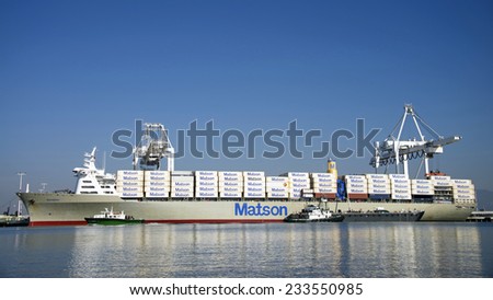 OAKLAND, CA - NOVEMBER 27, 2014: Foss POINT VINCENTE Tug Boat providing services to Matson Cargo Ship MAHIMAHI while the ship unloads and loads cargo at the Port of Oakland.