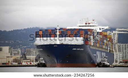 OAKLAND, CA - NOVEMBER 29, 2014:  After turning CMA CGA NORMA 180 degrees in the Inner Harbor, the tugboats return to their positions to resume escorting the ship away from the Port of Oakland.
