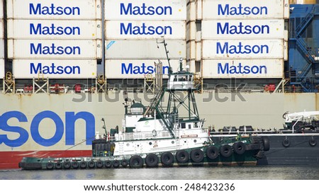 OAKLAND, CA - JANUARY 28, 2015: Tugboat POINT FERMIN pushing a Barge Ship next to Matson Cargo Ship MOKIHANA. Crews will utilize the barge to provide maritime services to the vessel.