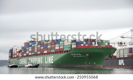 OAKLAND, CA - FEBRUARY 07, 2015: CSCL Cargo Ship YELLOW SEA, built in 2014, has a Gross Tonnage of 116,568. The vessels size necessitates the use of Four Tugboats to assist it to the Port of Oakland.