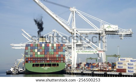 OAKLAND, CA - FEBRUARY 26, 2015: ROYAL MELBOURNE Tugboat with BERNE BRIER Barge providing Services for CSCL  AMERICA while loading at the Port of Oakland. Shipping containers seen lining the dock.