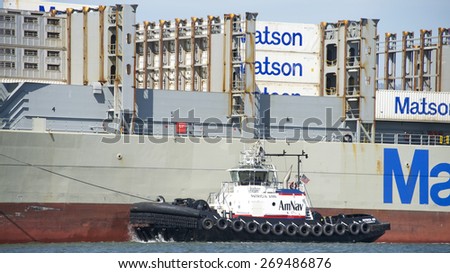 OAKLAND, CA - APRIL 13, 2015: PATRICIA ANN on the Port side of Matson Cargo Ship MAUI assisting the vessel maneuver into the Port of Oakland. A tugboat maneuvers vessels by pushing or towing them.