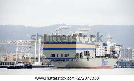 OAKLAND, CA - APRIL 22, 2015: Cargo Ship MOKIHANA entering the Port of Oakland. Tugboats work together to  turn the ship 360 degrees in the Middle Harbor prior to docking