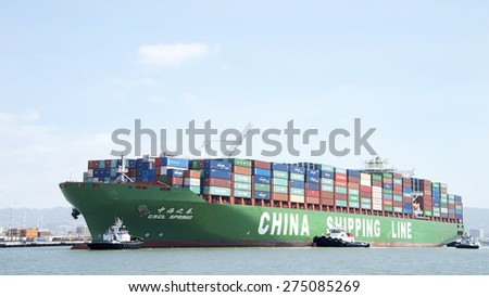 OAKLAND, CA - MAY 03, 2015: China Shipping Lines Cargo Ship CSCL SPRING entering the Port of Oakland with multiple tugboats assisting the vessel to maneuver.