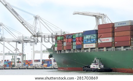 OAKLAND, CA - MAY 22, 2015: Tugboat SANDRA HUGH off the Port Bow of Evergreen Cargo Ship EVER CHAMPION, assisting the vessel to maneuver into the Port of Oakland.