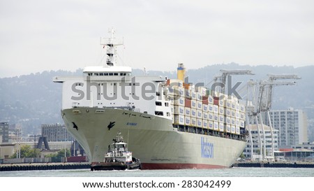 OAKLAND, CA - MAY 27, 2015:  AmNav Tugboat LIBERTY at the bow of Matson Cargo Ship MAHIMAHI, assisting the vessel to maneuver into the Port of Oakland.