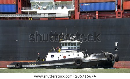 OAKLAND, CA - JUNE 04, 2015: Tugboat Z-FIVE off the starboard side of APL Cargo Ship DUBLIN, assisting the vessel to maneuver out of the Port of Oakland.