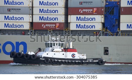 OAKLAND, CA - AUGUST 05, 2015: Cargo Ship VETERAN off the port side of Matson Cargo Ship MAHIMAHI, assisting the vessel into the Port of Oakland.