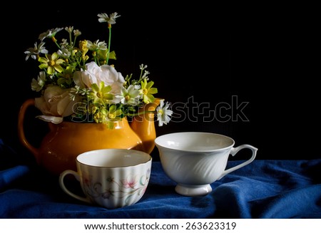 Flower in a yellow tea pot and vintage cup of coffee,cozy home rustic decor, cottage living, still life image dark tone