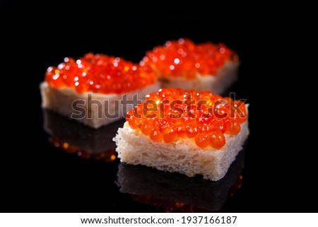salmon caviar on a piece of white kanape bread on a black background Stock fotó © 