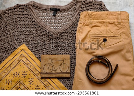 Outfit of casual woman. Brown sweater and a yellow scarf leather wallet belt shorts on a wooden background.