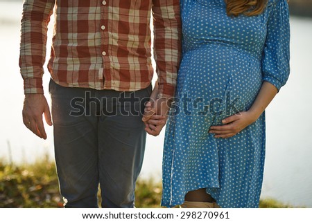 Happy pregnant woman and her husband in the park