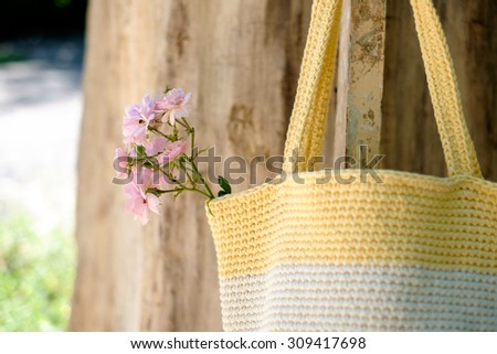knitted crochet bag of yellow color on the background of nature