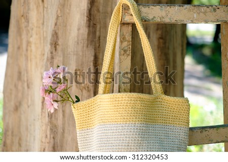 knitted crochet bag of yellow color on the background of nature