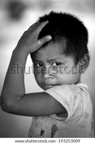 MARANKIARI, PERU - NOVEMBER 25, 2012: Photo of an unidentified AshaÂ¡ninka child touching his head in a little indian village. Processed in B&W.