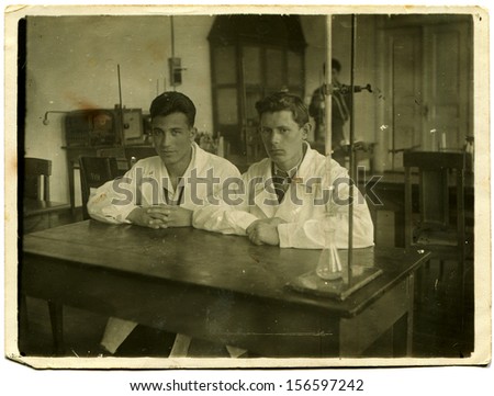UKRAINE - CIRCA 1950s: two young men in white coats are sitting at a table in training chemistry lab, Kharkov, Ukraine, 1950s