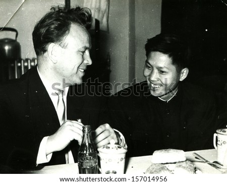 CHINA - CIRCA 1958: member of the Soviet delegation talks with his Chinese counterpart at the dinner table in front of them is a bottle of Coca-Cola, Chinese People's Republic, 1958