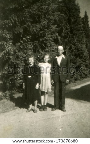 GERMANY, ROSTOCK - 1940s: An antique photo shows man and woman standing together with her teenage daughter on the footpath in the park