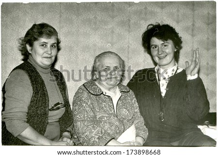 GERMANY - 1960s: An antique photo shows three women of different generations sitting on the bed