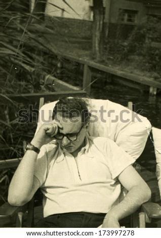 GERMANY -  1950s: An antique photo shows man reading a book while sitting in a chair in the garden