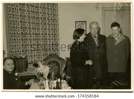 GERMANY -  CIRCA 1960s: An antique photo shows young woman greets guests who came to the home celebration