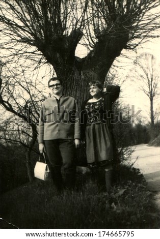 GERMANY -  CIRCA 1960s: An antique photo shows man and woman posing under the tree, autumn