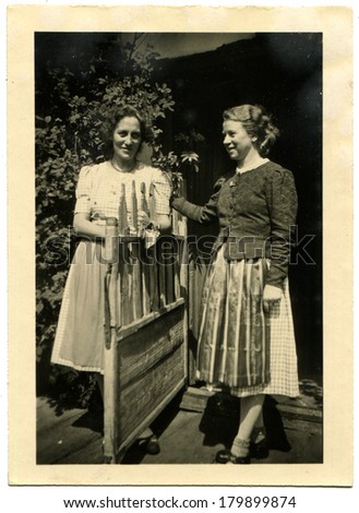 GERMANY - CIRCA 1950s: An antique photo of Two young beautiful girls posing near the open gate of garden