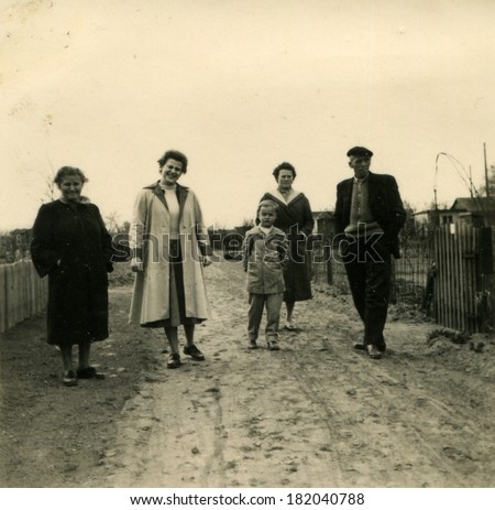 GERMANY, ROSTOCK - CIRCA 1950s: An antique photo of family posing on dirty road on the street
