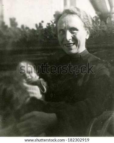 GERMANY - CIRCA 1944: An antique photo of middle-aged woman posing with a baby in her arms, 1944