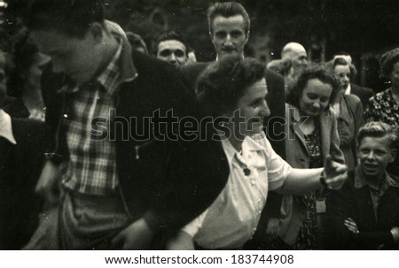 GERMANY - CIRCA 1950s: An antique photo shows middle-aged woman in a white blouse among the people during the holiday