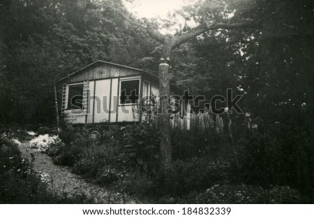 LIECHTENSTEIN - CIRCA 1940s: An antique photo of man looks out the window of a small house in the woods