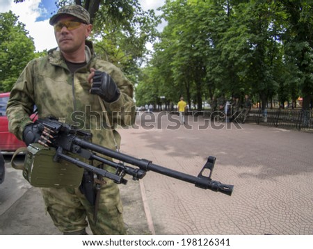 LUHANSK, UKRAINE - June 9, 2014: Armed with a machine gun pro-Russian fighter in the park near the building of Luhansk Regional Administration