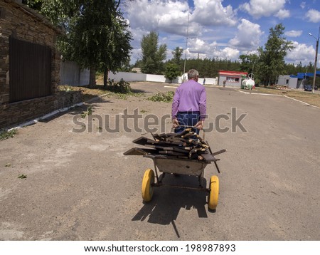 MAKAROVO, LUHANSK REGIPN, UKRAINE - June 13, 2014: An elderly man carries home on the trolley planks of Restaurant \