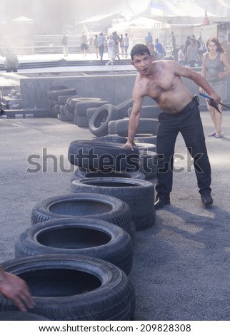 KYIV, UKRAINE - Aug 7, 2014: Bare-chested man puts in a tire to the barricade. -- Activists and police have clashed in the Ukrainian capital\'s center after communal workers tried to dismantle camp